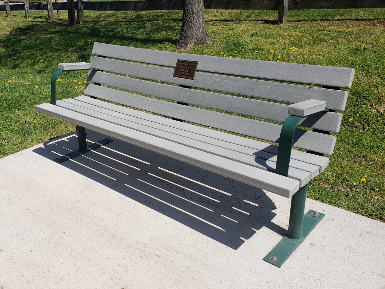 Grey bench next to paved trail