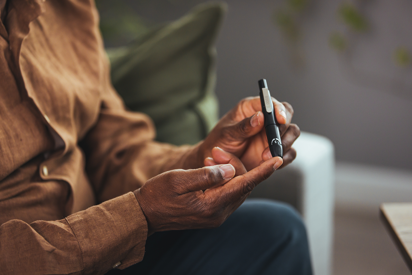 Senior man with glucometer checking blood sugar level at home