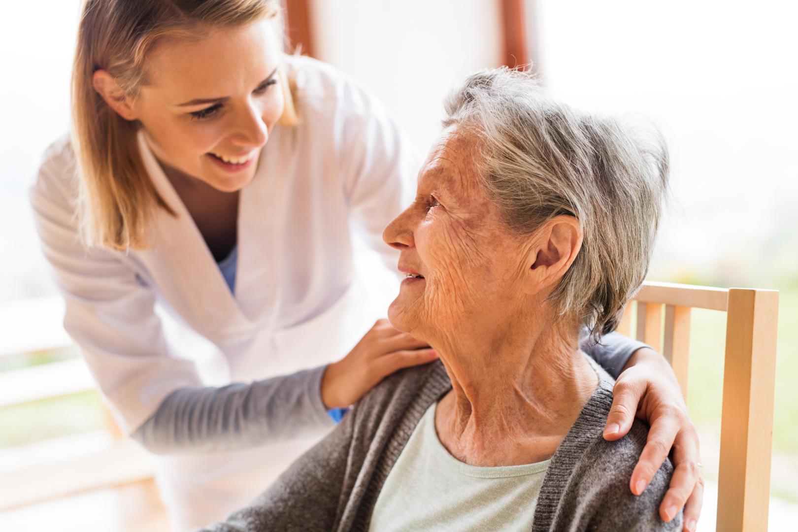 An older adult being helped by an aide in her home.